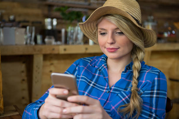 istock Woman wearing hat while using mobile phone in coffee shop 845277456