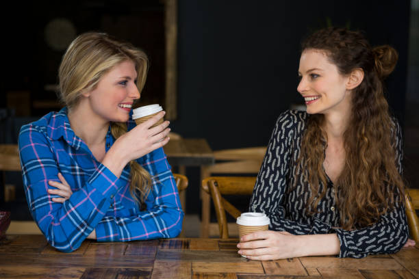 istock Smiling female friends having coffee while talking in cafe 845277892