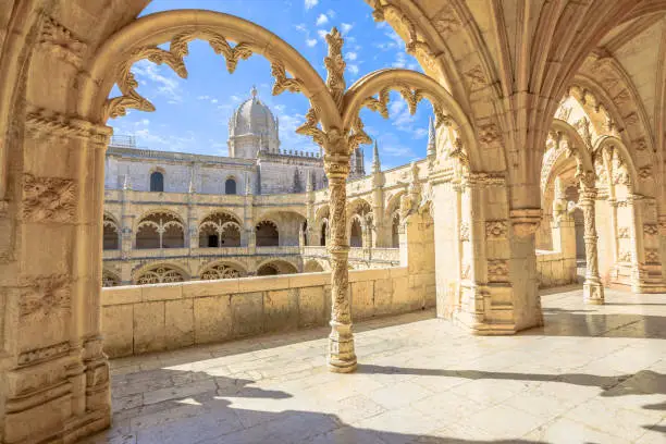 Beautiful reticulated vaulting on courtyard or cloisters of Hieronymites Monastery, Mosteiro dos Jeronimos, famous Lisbon landmark in Belem district and Unesco Heritage. Church dome on background.