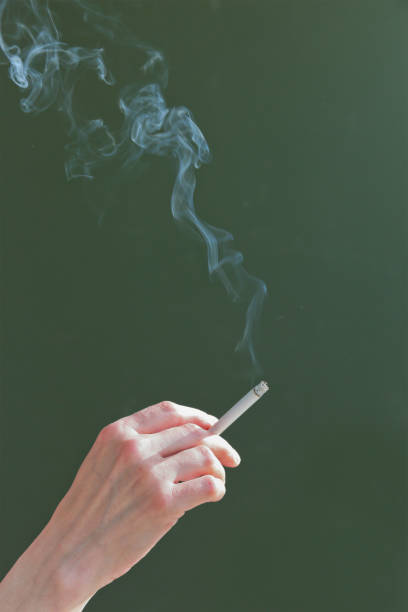 istock Hand with a cigarette and cigarette smoke on a dark background 845290274