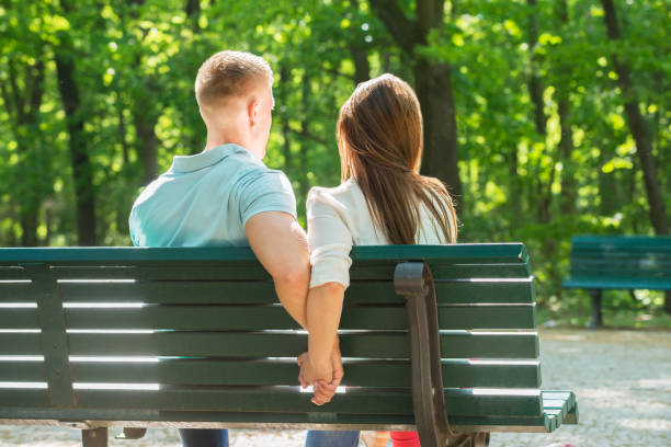 istock Couple Sitting On Bench Together And Holding Hands 845292934