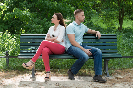 Unhappy Couple Sitting Back To Back On Bench In Park