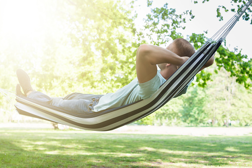 Young Man Relaxing In Hammock At Park