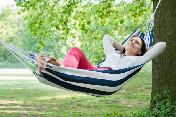 Woman Relaxing In Hammock Young Happy Woman Relaxing In Hammock At Garden hammock relaxation women front or back yard stock pictures, royalty-free photos & images