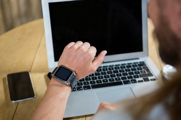 istock Man using smart watch with laptop and mobile phone on table in cafe 845304946