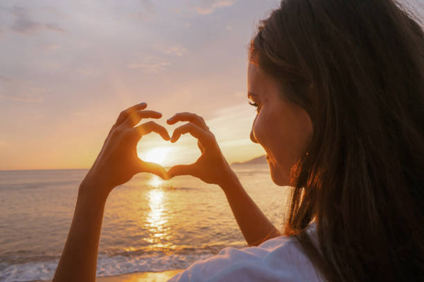 istock Woman making heart of hands at sunset 845307748