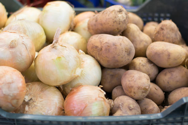 Potatoes and onions in the market. Potatoes and onions in the market inside a plastic basket. onion family stock pictures, royalty-free photos & images