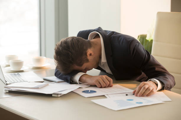 istock Tired young businessman sleeping on desk in office 845314336