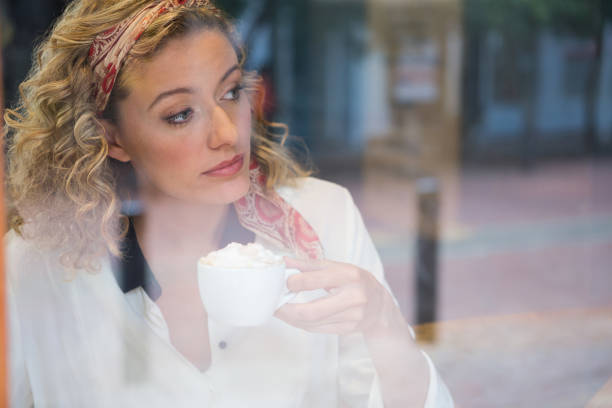 istock Woman having coffee seen through cafe window 845329196