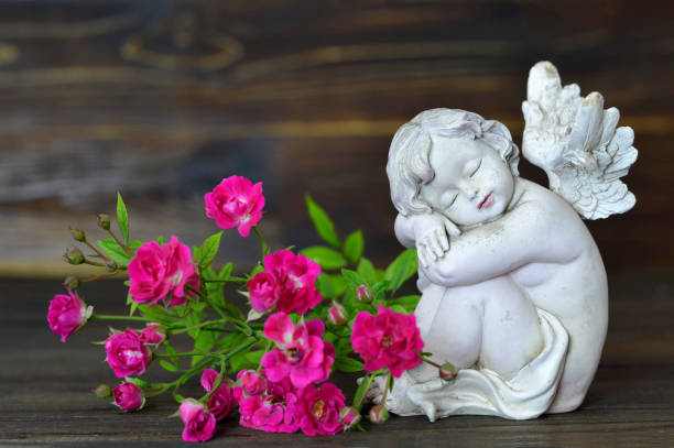 istock Sleeping angel and roses on wooden background 845348380