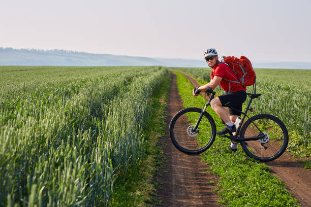 istock Young cyclist riding bicycle on the road on green field. 845350854