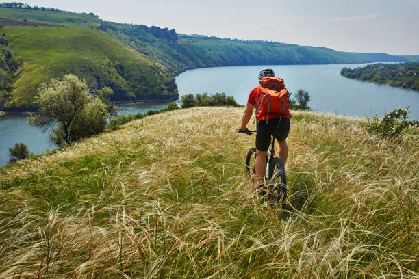 istock Young cyclist riding mountain bicycle through green meadow against beautiful sky. 845350918