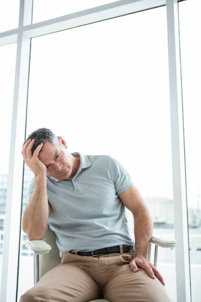 istock Tensed man sitting on chair against window 845354990