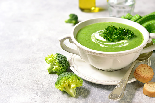 Broccoli soup in a white bowl on a light slate,stone or concrete background