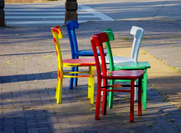istock Five colored chairs sitting on a sidewalk in a park 845361198