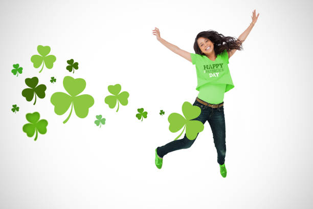Girl wearing patricks day tshirt jumping for joy on white shamrock background