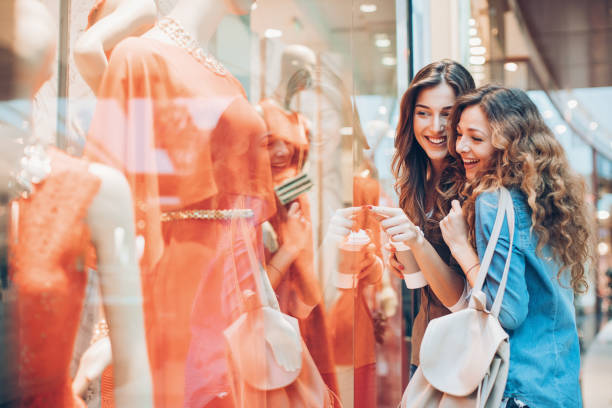 Happy girls window shopping Happy girfriends in a fashion store window shopping stock pictures, royalty-free photos & images