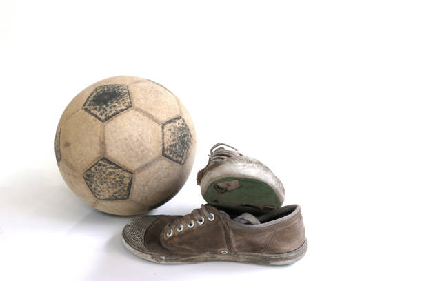 fútbol antiguo y zapatos viejos aislados sobre fondo blanco - pauper fotografías e imágenes de stock