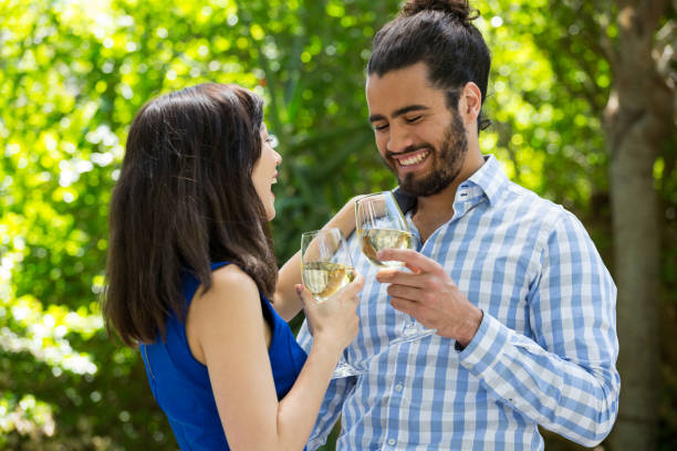 istock Cheerful couple toasting wine glasses in park 845408634