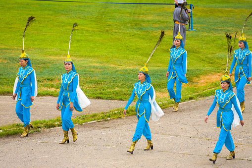 Beautiful Mongolian females dressed in colorful blue costume walking in the opening ceremony of the Naadam Festival