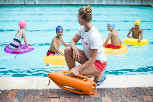 istock Lifeguard holding rescue can while children swimming in pool 845435586