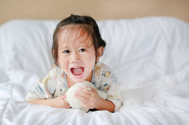istock Cute little girl with teddy bear lying on bed. 845446942