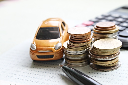 Business, finance, saving money, banking or car loan concept : Miniature car model, coins stack, calculator and saving account book or financial statement on office desk table