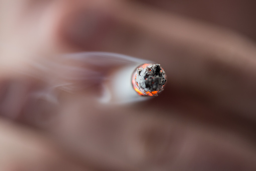 Focus on tip of burning cigarette being smoked by man
