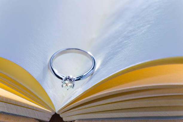 istock beautiful diamond ring on blank open book with cool and warm color tone, room for copy space, good concept for wedding, engagement, or special occasions 845464614