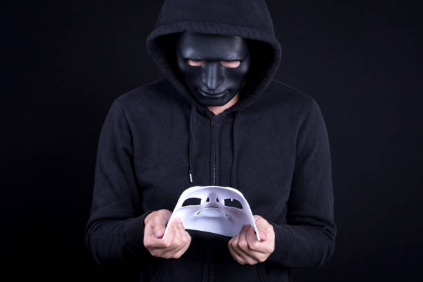istock Mystery man wearing black mask holding and looking at white mask 845464904