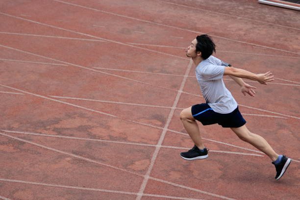 istock Athletic handsome young Asian runner sprinter crossing the finish line on track in stadium. 845467664