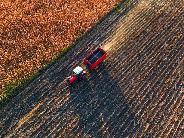 Photo of Aerial view of farmer driving agricultural tractor and trailer full of grain