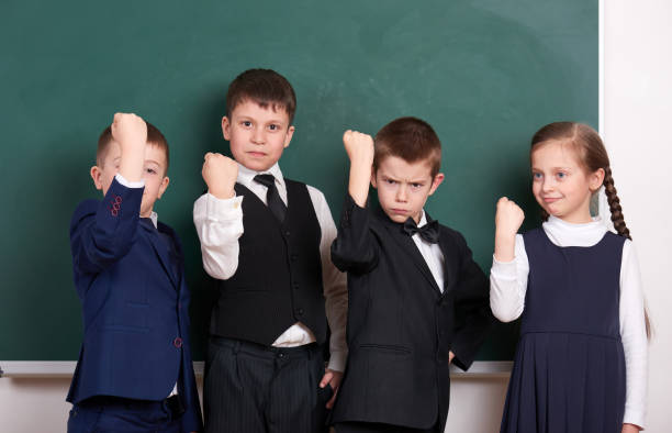 istock group pupil as a gang show knuckle, posing near blank chalkboard background, grimacing and emotions, friendshp and education concept 845482990