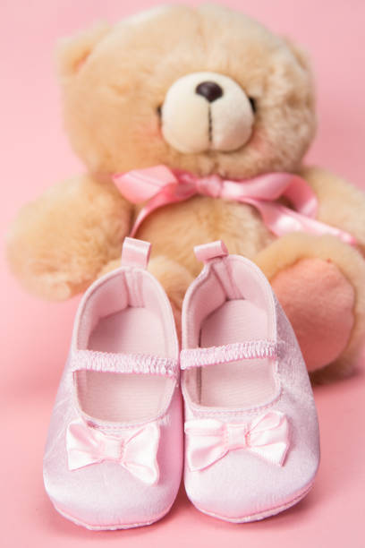 istock Pink baby booties and teddy bear 845490170