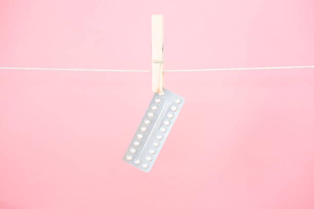 Contraceptive pill blister pack hanging from line Contraceptive pill blister pack hanging from line on pink background contraceptive photos stock pictures, royalty-free photos & images