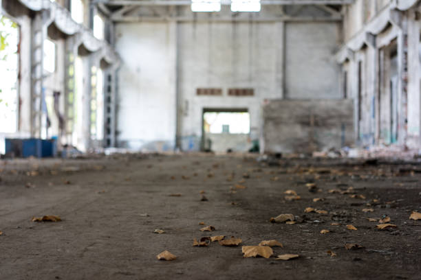 Interior of old factory buildings destroyed. Ruins of industrial enterprise, dark debris destroyed factory premises in factory as result of economic crisis and earthquake.