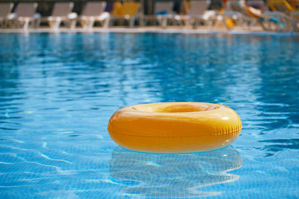 schwimmring auf blauem wasser cooles - swimming pool inner tube toy float stock-fotos und bilder