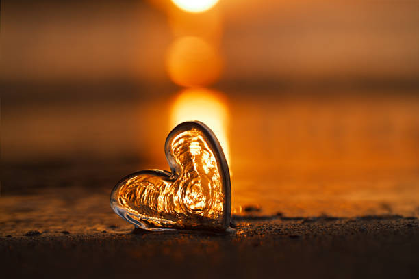 clear glass heart on  sand beach with sunrise sun light, Canary island, Spain