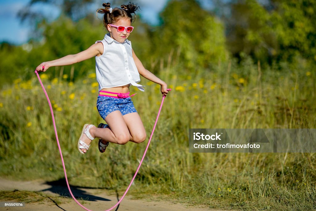 girl jumping with a rope little girl jumping rope on nature Jump Rope Stock Photo