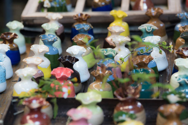 selective focused closeup multicolored colorful traditional clay sculpture spiral flower vases on the wooden shelf