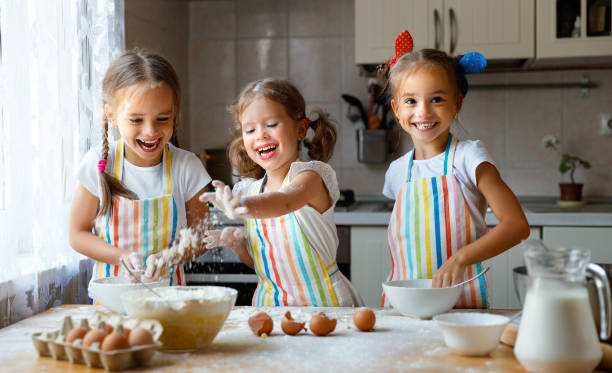 soeurs heureux enfants filles cuire cookies, pétrissent la pâte, jouent avec la farine et le rire - rolling dough pastry apron photos et images de collection