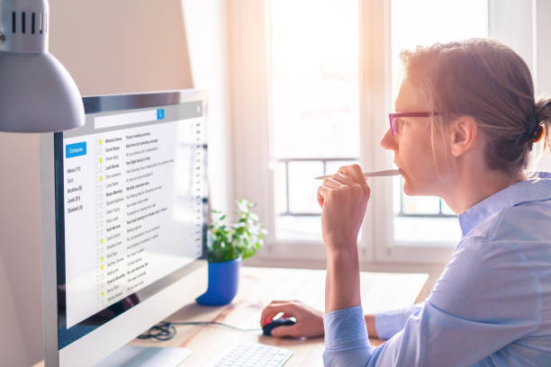 female business person reading email on computer screen at work - e mail imagens e fotografias de stock