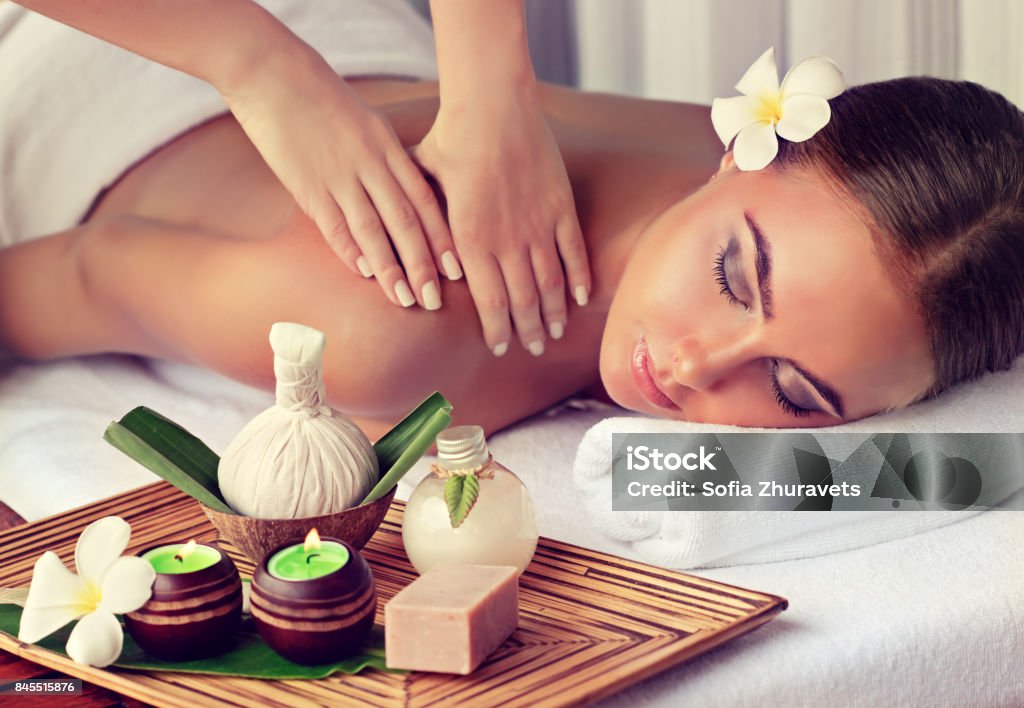 Woman is getting massage in the spa salon. Young lady is laying on massage table and gets massage treatment.Spa and body massage.Woman is getting massage in the spa salon. Massaging Stock Photo