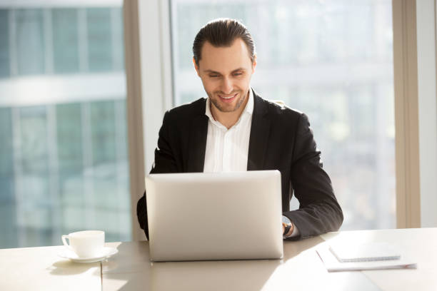 istock Smiling handsome businessman working on laptop in office. 845516092