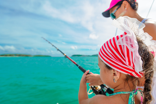 A girl and her mom fishing on a boat. Colorful tropical pattern around.