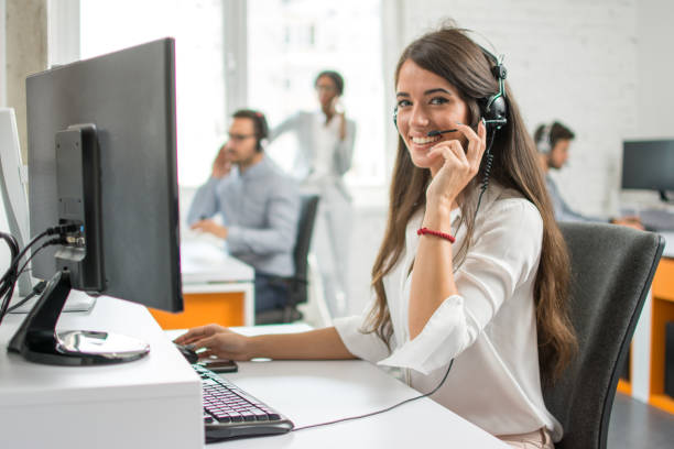 junge freundliche bedienerin agentin mit headsets, die in einem callcenter arbeiten. - on the phone customer service representative beautiful business person stock-fotos und bilder