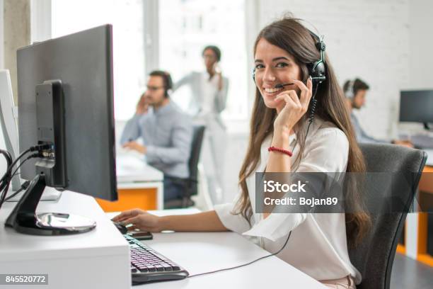 Agente De Mujer Joven Amable Operador Con Auriculares En Un Centro De Llamadas Foto de stock y más banco de imágenes de Agente de servicio al cliente