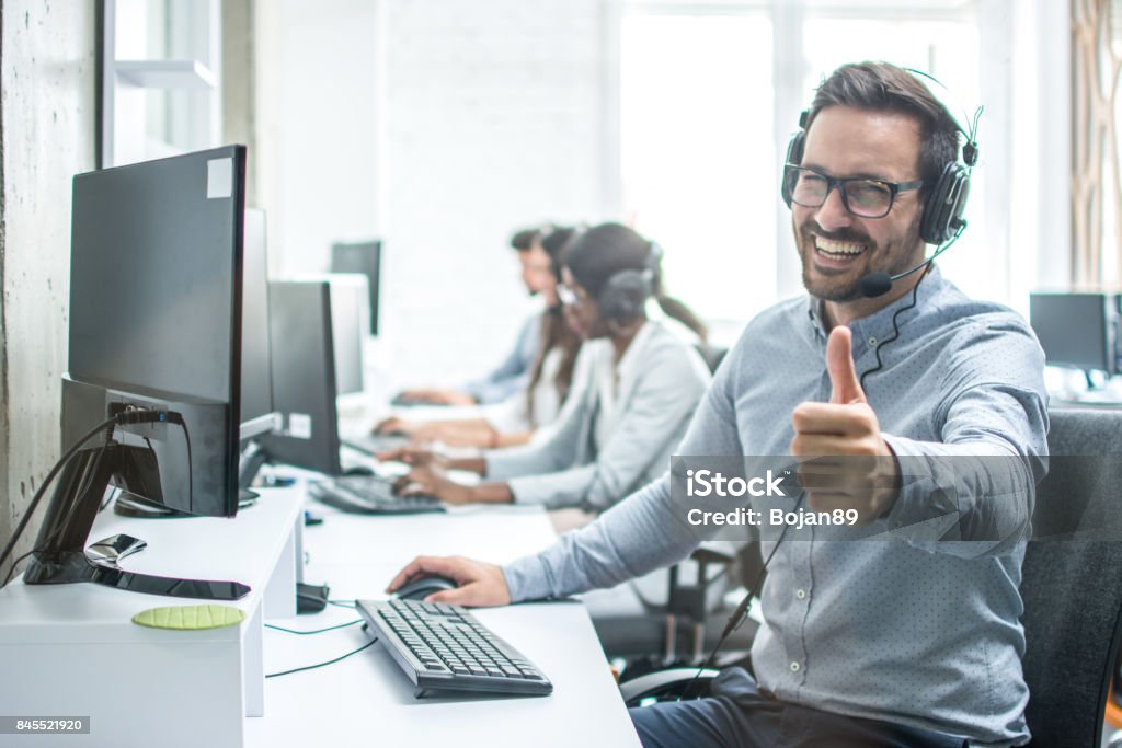 Operador de servicio de cliente masculino alegre mostrando los pulgares para arriba en oficina. - Foto de stock de Pulgar hacia arriba libre de derechos