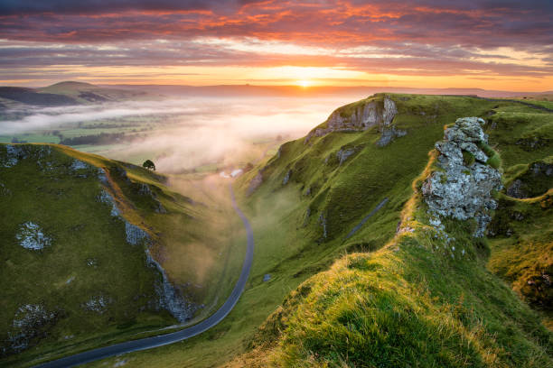 route sinueuse au lever du soleil dans le peak district. - fog road spooky mist photos et images de collection