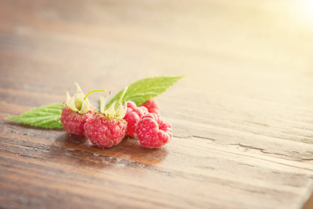 Wild raspberry with leaves on wooden background